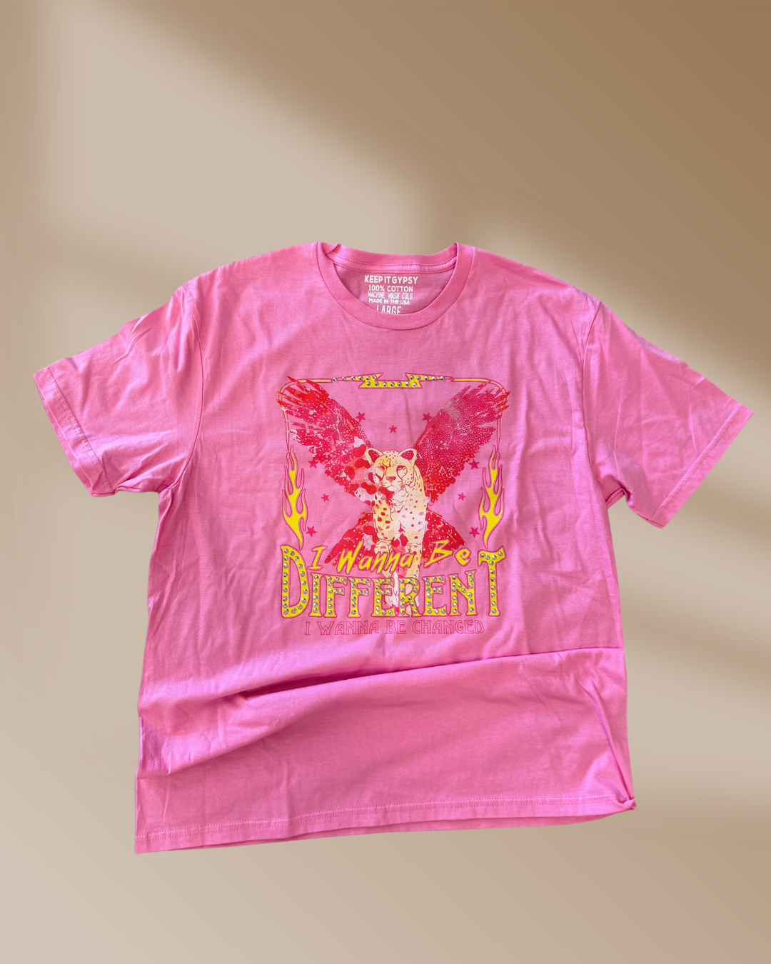 Pink t-shirt with graphic design and text on a beige background