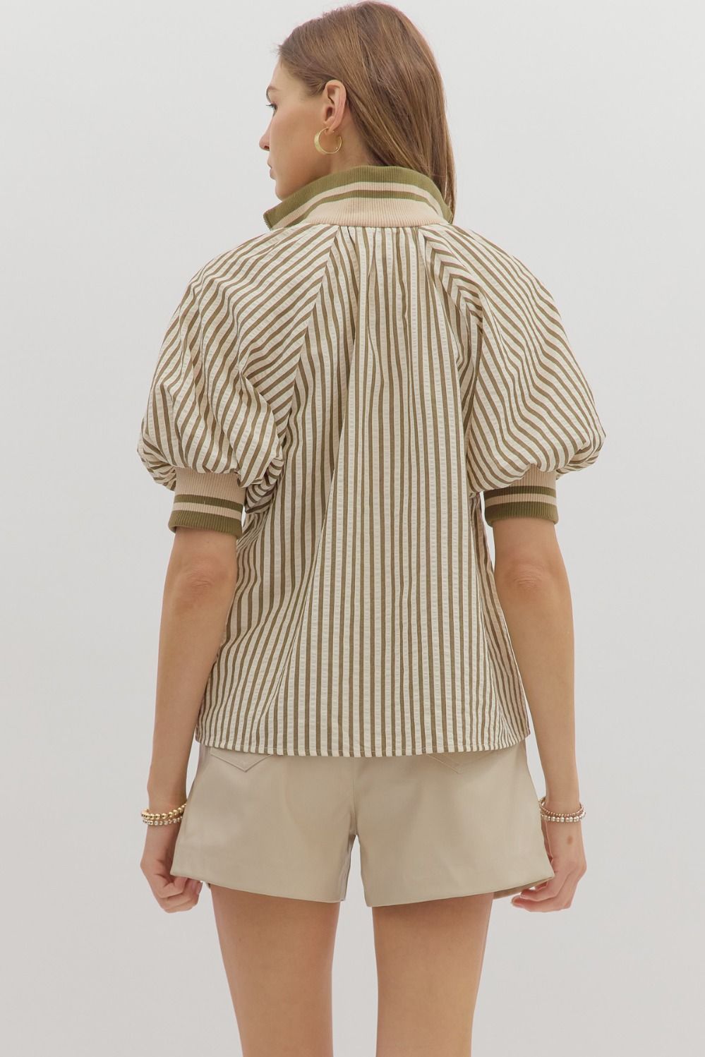 Woman wearing a striped shirt and beige shorts on a plain background