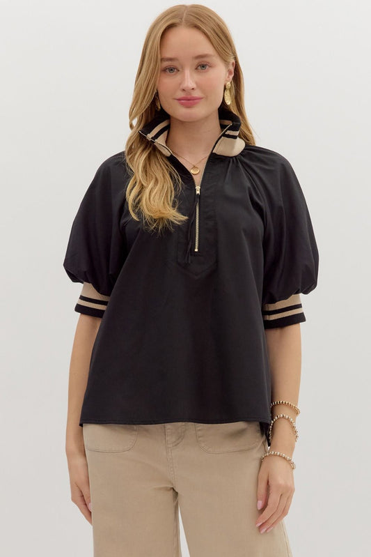 Woman wearing a black top with beige accents on a white background