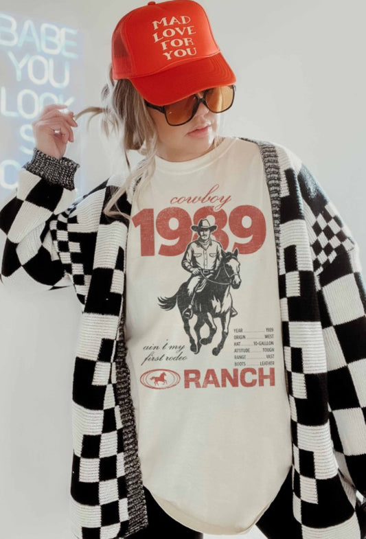 Person wearing a red cap, sunglasses, and a checkered cardigan over a graphic t-shirt with text and graphics.
