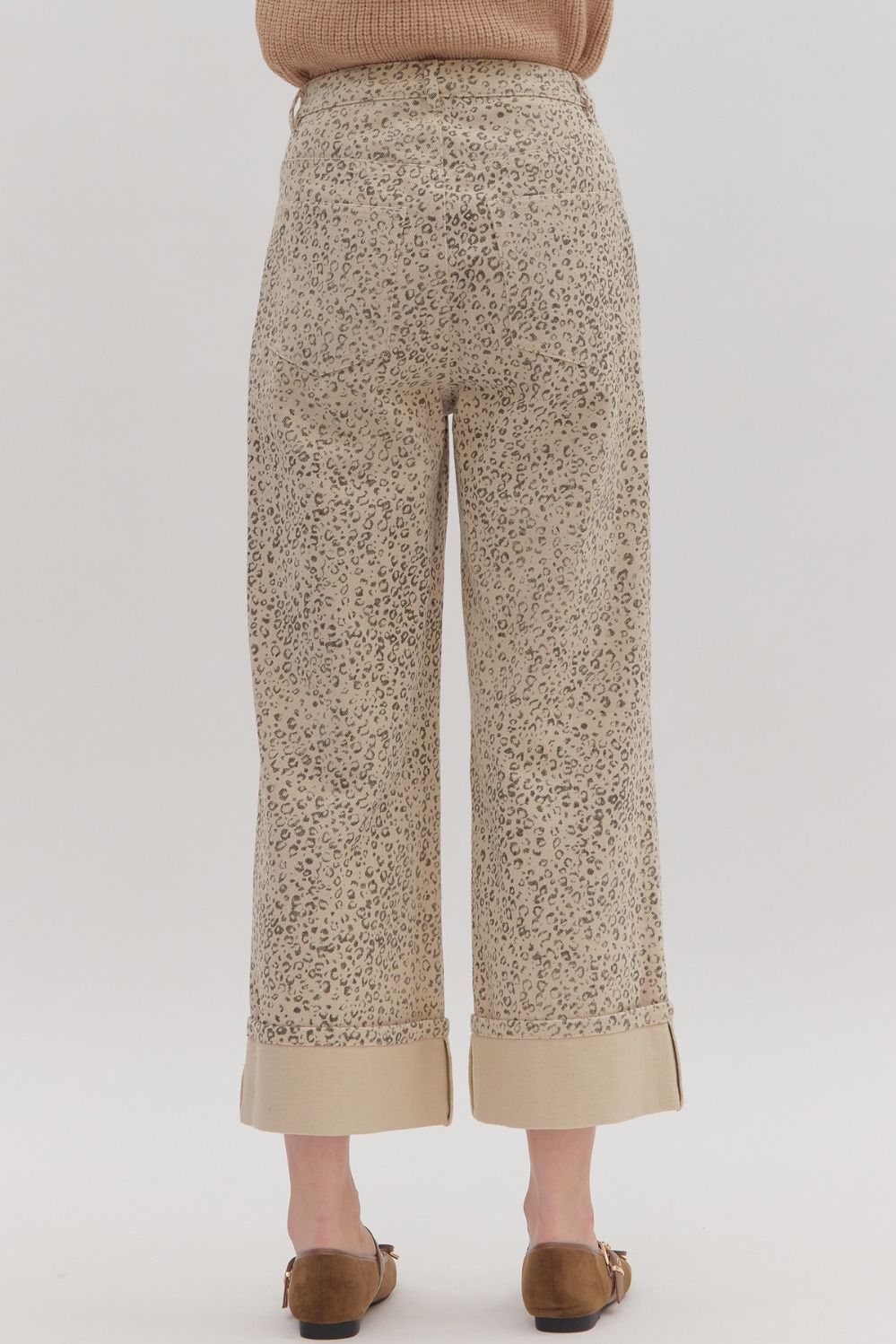 Leopard patterned pants worn by a person on a plain background