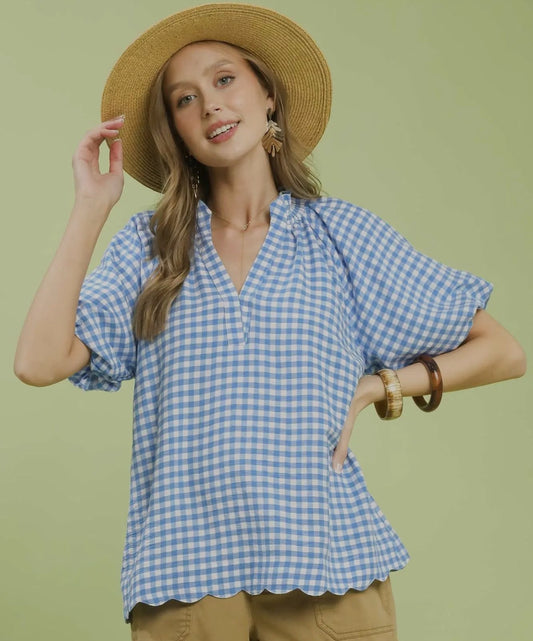 Woman wearing a blue checkered blouse and straw hat on a green background