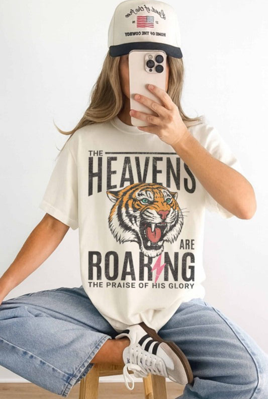 Person wearing a white t-shirt with a tiger graphic and text, sitting on a chair.