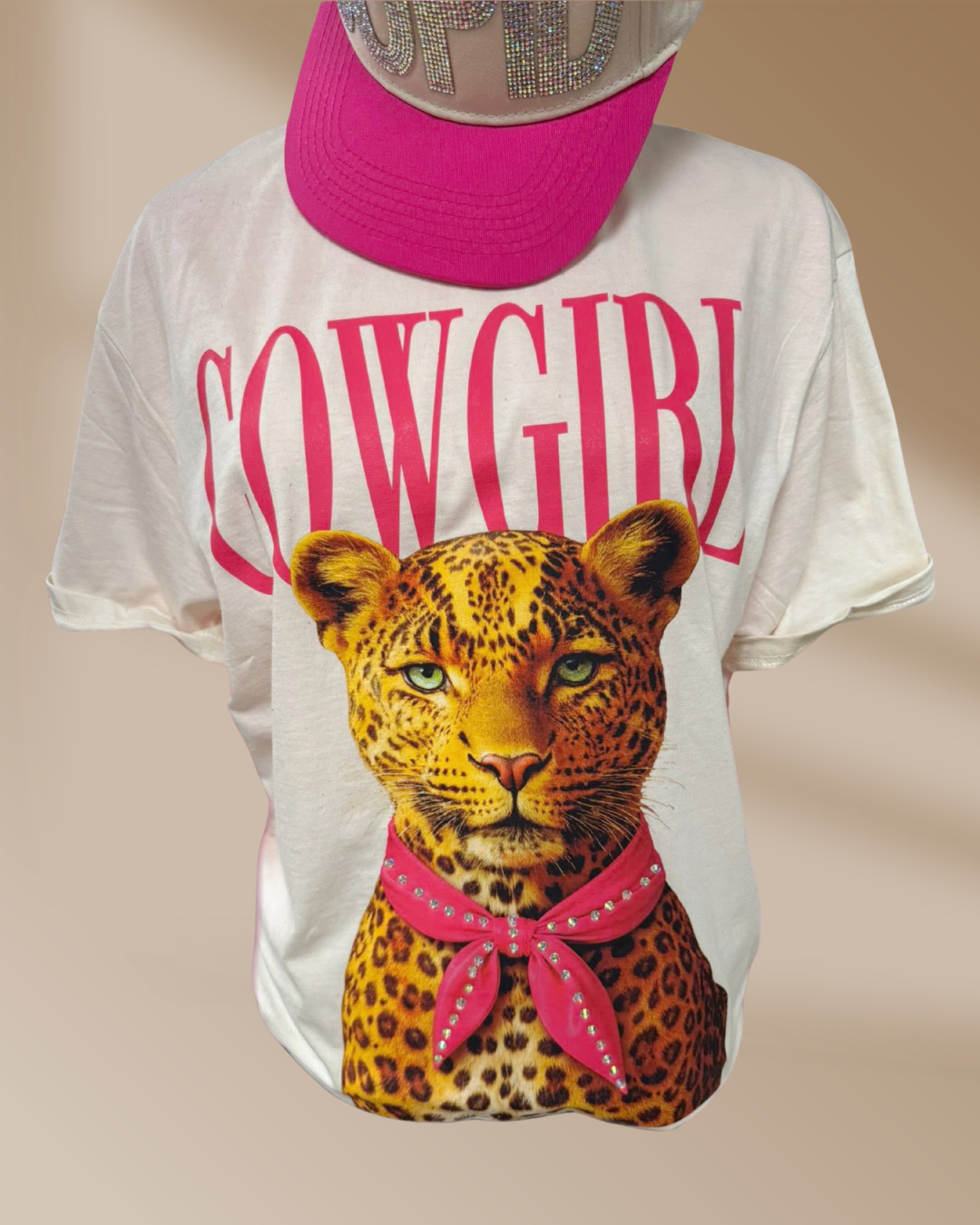 White t-shirt with a leopard graphic and 'COWGIRL' text, worn with a pink hat.