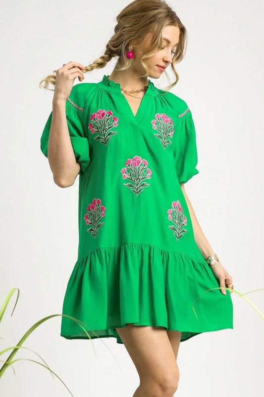 Woman wearing a green dress with floral embroidery on a white background